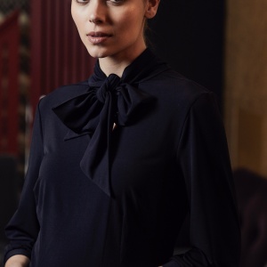 A model wearing a navy blue pussy bow dress