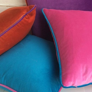 4 velvet cushions in different colours stacked on top of each other